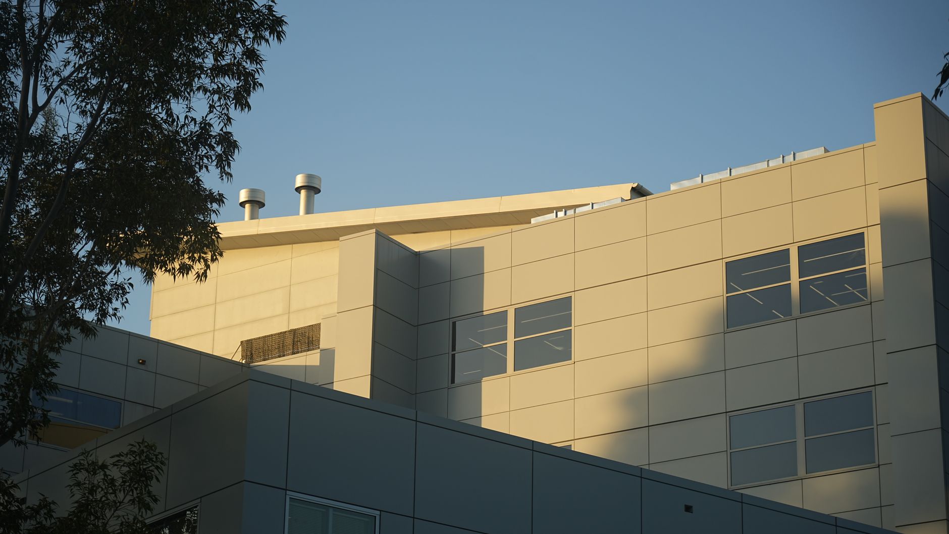 Sunlit modern building facade with geometric design and clear sky.