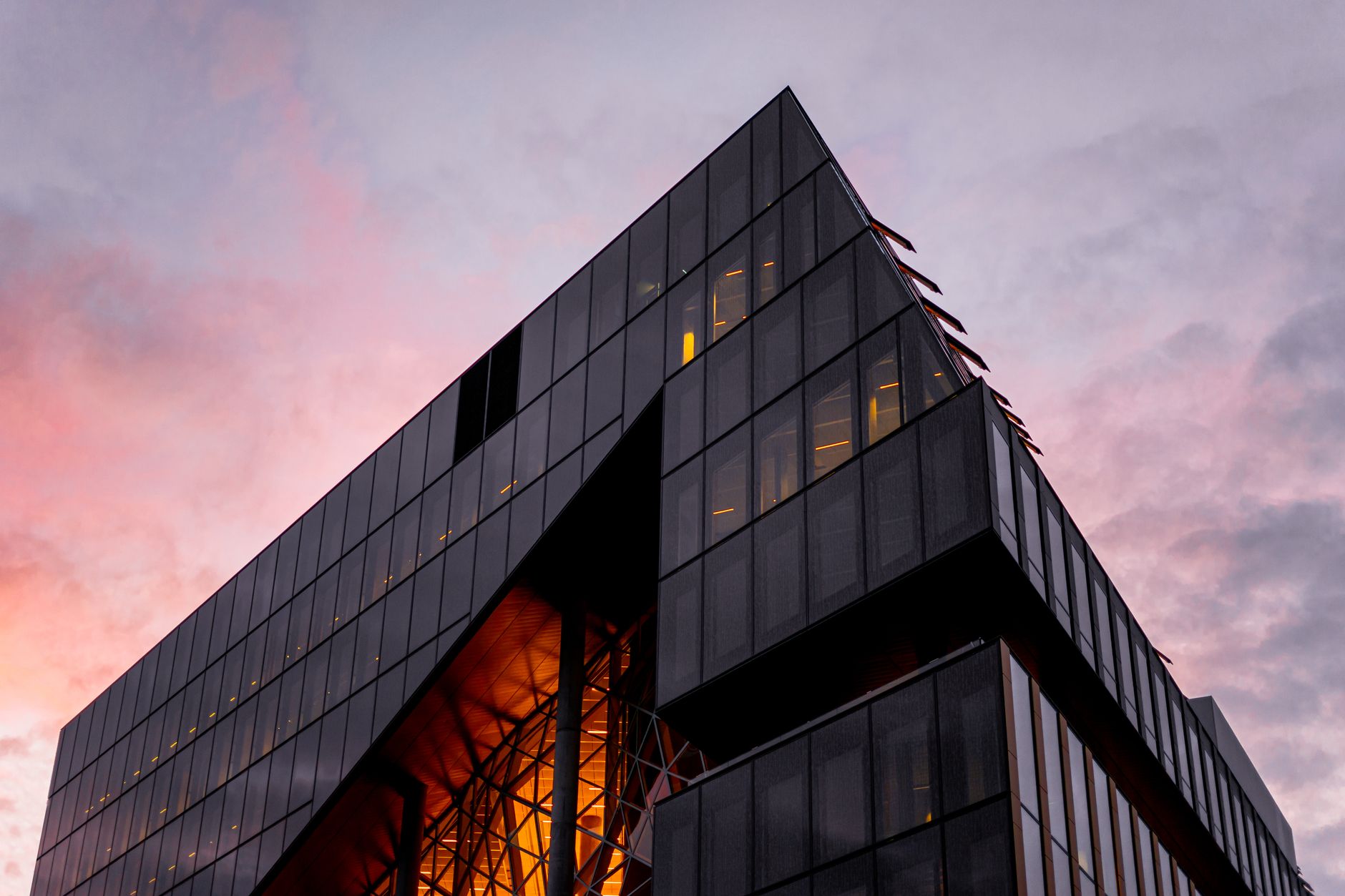 A striking modern skyscraper with glass facade reflecting a vibrant sunset sky.